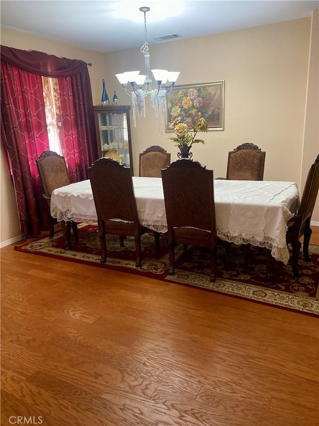 dining area featuring wood-type flooring and a chandelier