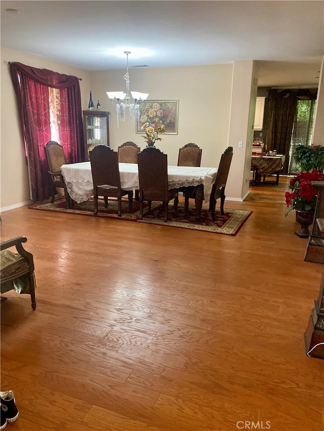 dining space with wood-type flooring, a chandelier, and plenty of natural light