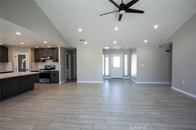 kitchen featuring stainless steel stove, light hardwood / wood-style flooring, lofted ceiling, and ceiling fan