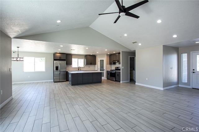 kitchen with ceiling fan, stainless steel appliances, light hardwood / wood-style floors, and a center island