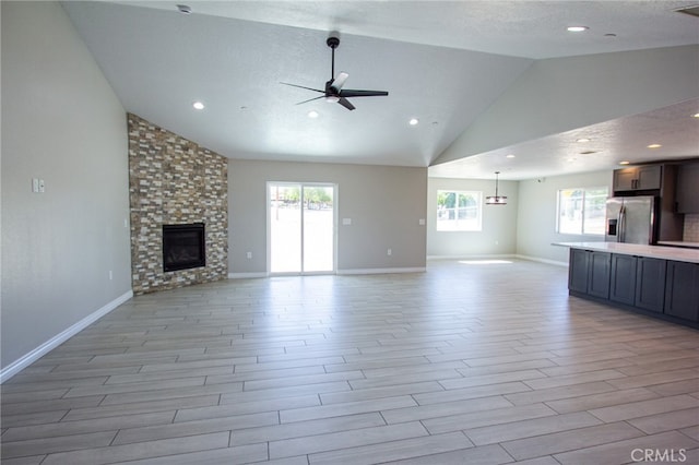 unfurnished living room with light wood-type flooring, a healthy amount of sunlight, a large fireplace, and ceiling fan