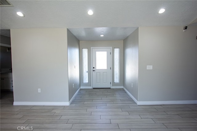 entrance foyer with a textured ceiling and light hardwood / wood-style floors