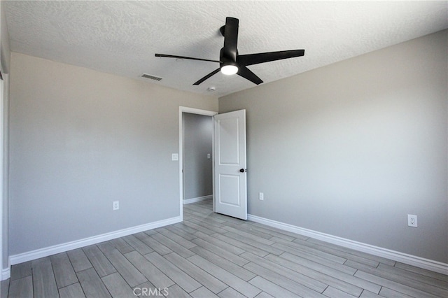 spare room featuring light hardwood / wood-style flooring, ceiling fan, and a textured ceiling