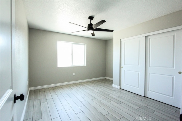 unfurnished bedroom featuring ceiling fan, a textured ceiling, a closet, and light hardwood / wood-style floors