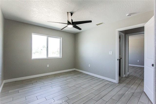 empty room featuring a textured ceiling, ceiling fan, and light hardwood / wood-style flooring