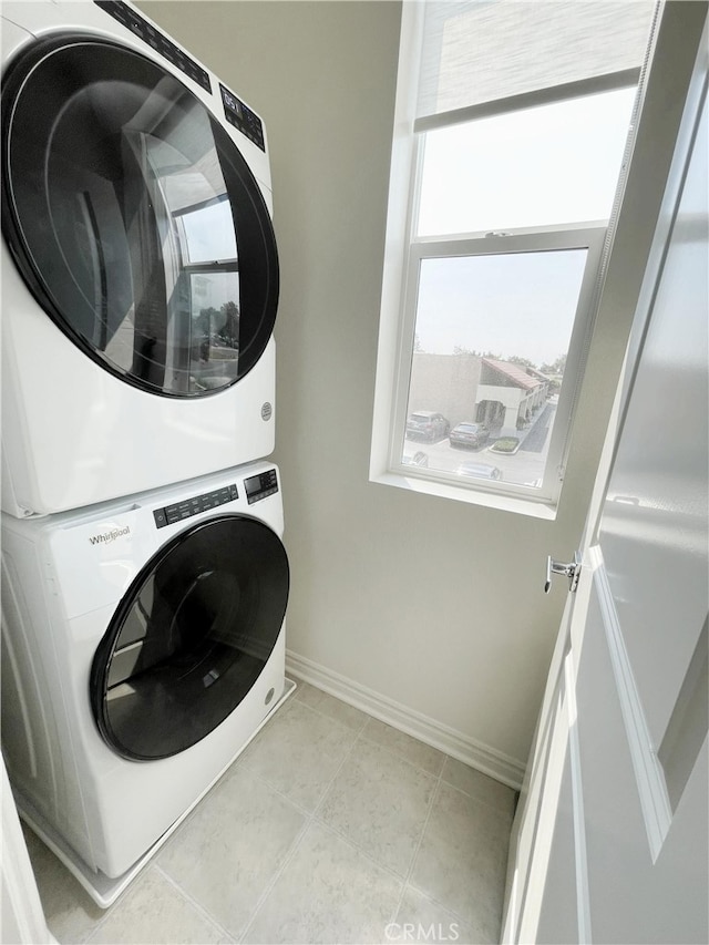 laundry area with stacked washer and clothes dryer and light tile patterned floors