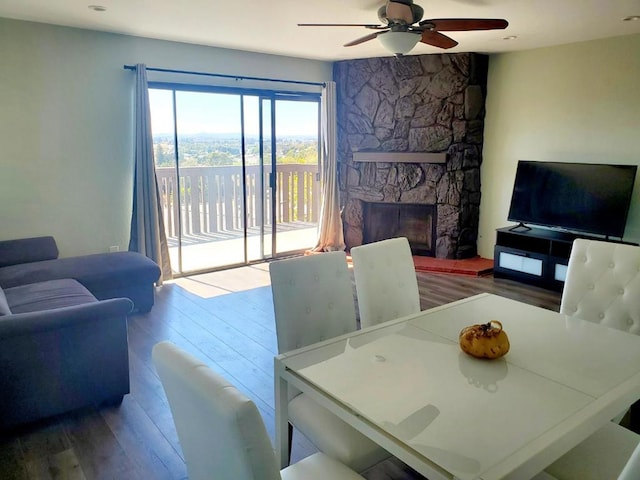 dining space with a fireplace, wood-type flooring, and ceiling fan