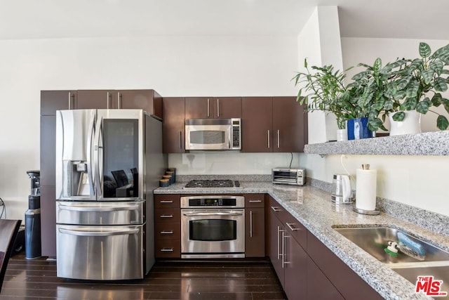 kitchen featuring appliances with stainless steel finishes, light stone countertops, dark brown cabinets, and dark hardwood / wood-style flooring