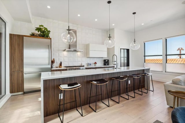 kitchen with hanging light fixtures, an island with sink, sink, and stainless steel appliances