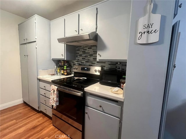 kitchen featuring backsplash, stainless steel electric range oven, and light wood-type flooring