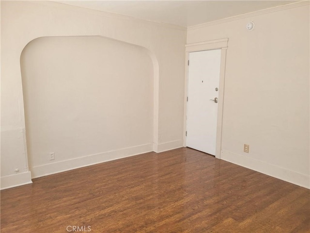 unfurnished room featuring ornamental molding and dark wood-type flooring