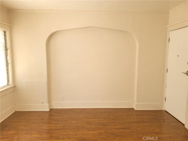 spare room featuring dark hardwood / wood-style flooring and crown molding