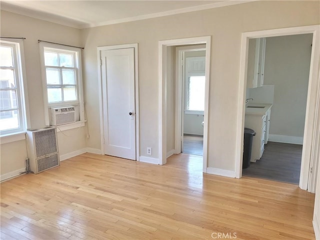 unfurnished bedroom featuring sink, light wood-type flooring, cooling unit, and connected bathroom