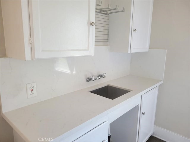 kitchen featuring decorative backsplash, white cabinetry, and sink