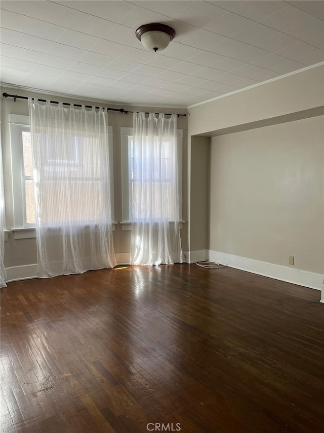 empty room with ornamental molding and dark wood-type flooring