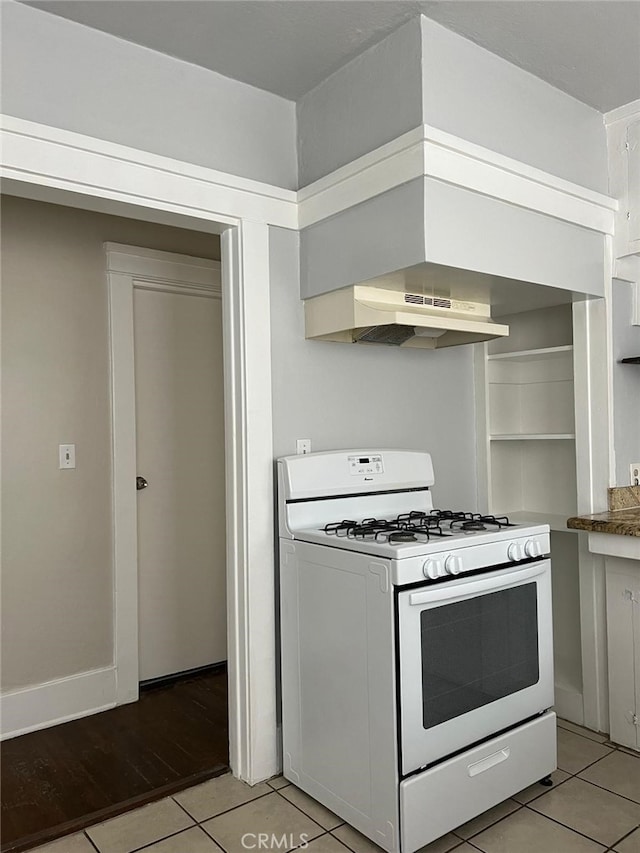 kitchen featuring ventilation hood, light tile patterned flooring, white cabinetry, and white range with gas cooktop