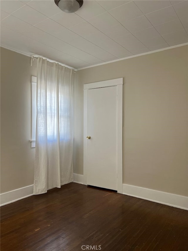 spare room featuring crown molding and dark wood-type flooring