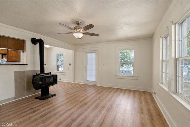 foyer entrance featuring ceiling fan, ornamental molding, a wood stove, a textured ceiling, and light hardwood / wood-style floors