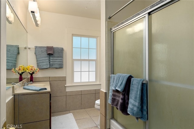 bathroom featuring vanity, toilet, a shower with door, and tile patterned floors