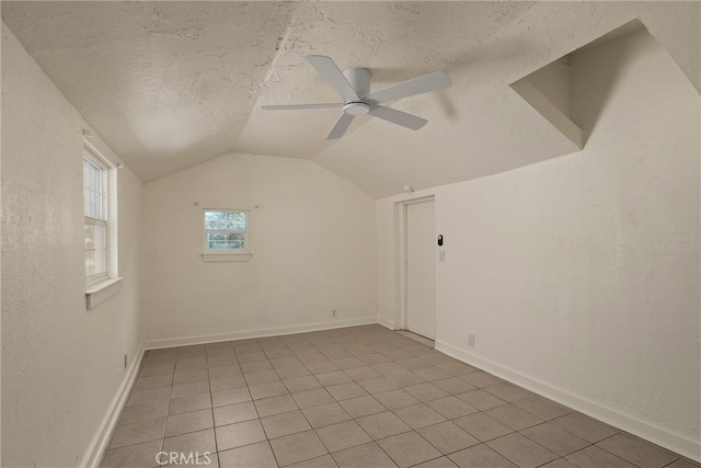 interior space with vaulted ceiling, ceiling fan, and a textured ceiling