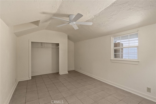 unfurnished bedroom with ceiling fan, lofted ceiling, light tile patterned floors, a textured ceiling, and a closet