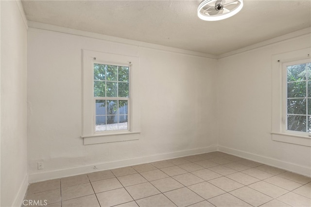 tiled spare room with a textured ceiling, crown molding, and a healthy amount of sunlight