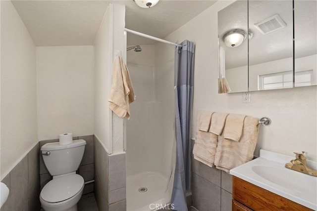 bathroom featuring tile walls, toilet, vanity, and curtained shower