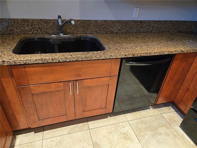 kitchen with sink, light tile patterned floors, dark stone counters, and black dishwasher