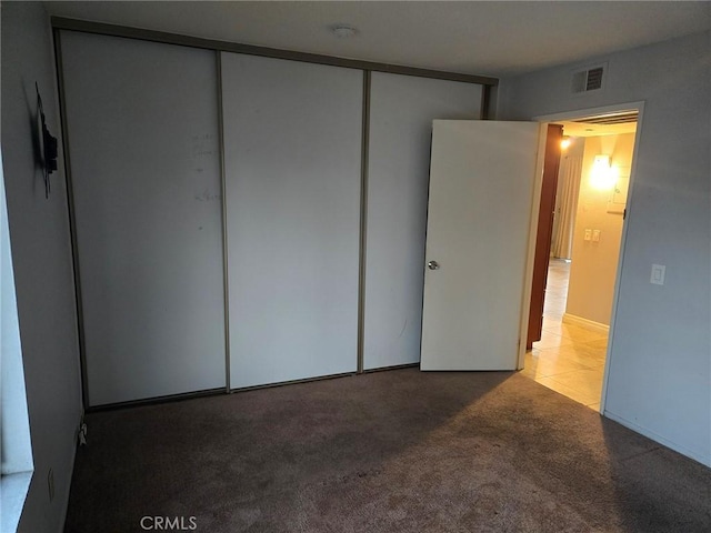 unfurnished bedroom featuring light carpet and a closet