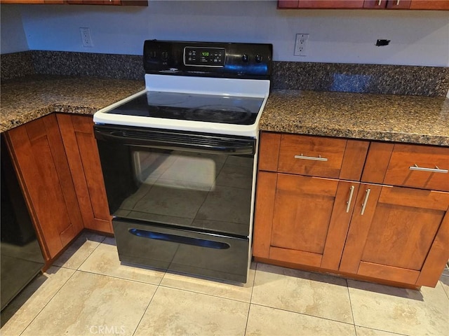 kitchen with white range with electric stovetop, dark stone counters, and light tile patterned flooring