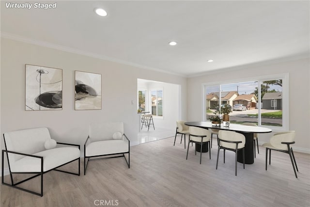 dining room with crown molding and light hardwood / wood-style flooring