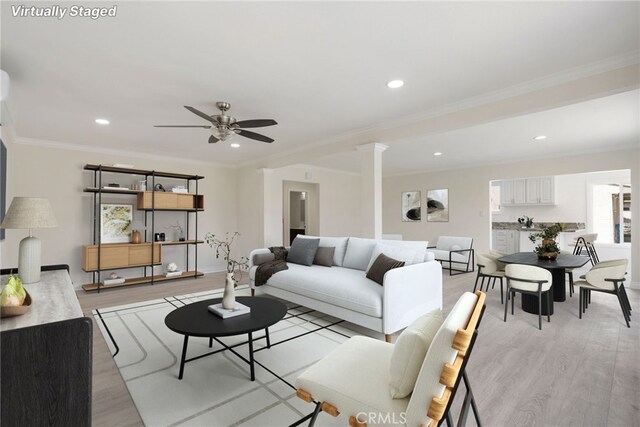 living room with ceiling fan, decorative columns, crown molding, and light hardwood / wood-style flooring