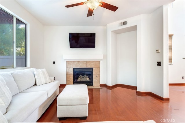 living room with a tile fireplace, hardwood / wood-style floors, and ceiling fan