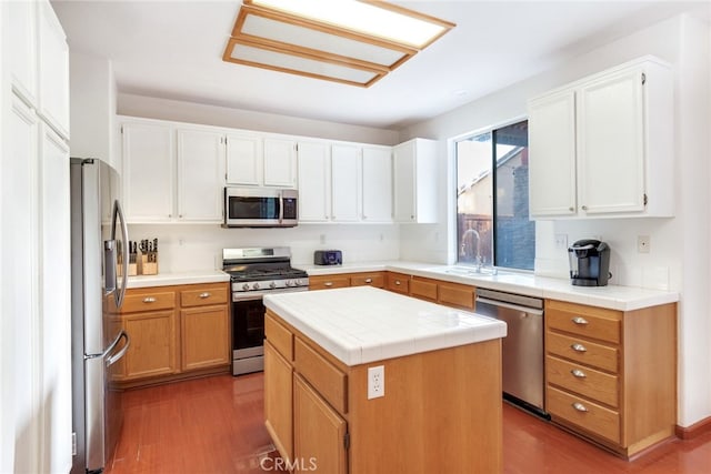 kitchen featuring white cabinets, sink, wood-type flooring, stainless steel appliances, and a center island