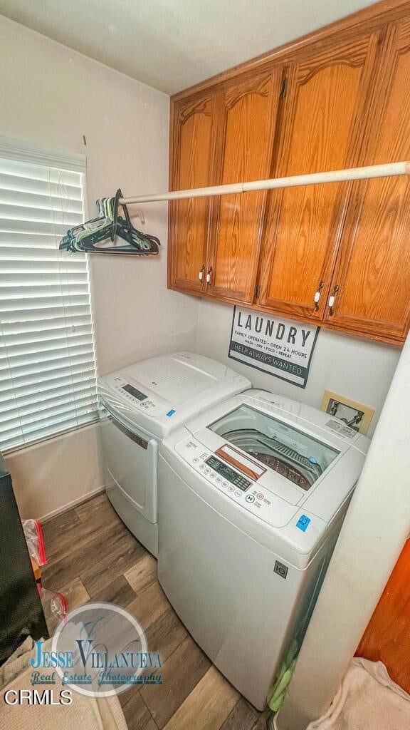 washroom with washing machine and clothes dryer, cabinets, and hardwood / wood-style floors