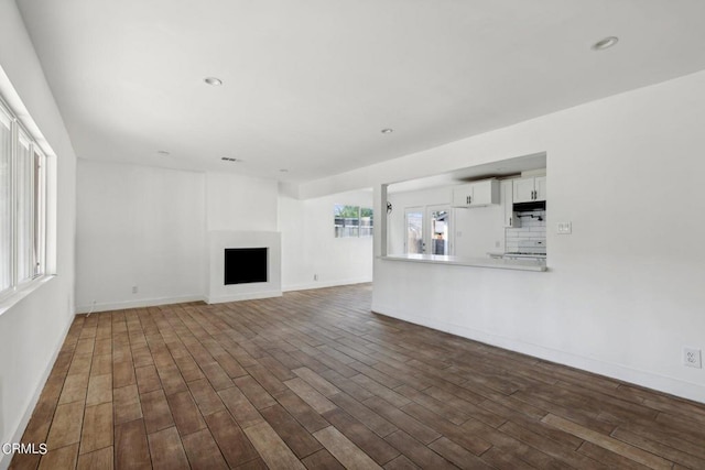 unfurnished living room with dark wood-type flooring and plenty of natural light