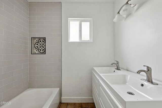 bathroom featuring vanity, hardwood / wood-style floors, and a tub to relax in