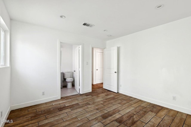 unfurnished bedroom with ensuite bath and dark hardwood / wood-style floors