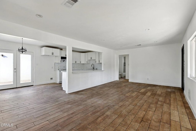 unfurnished living room with sink and wood-type flooring