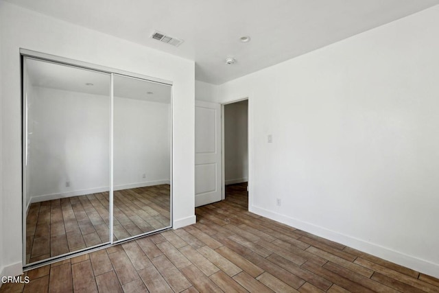 unfurnished bedroom with hardwood / wood-style flooring and a closet