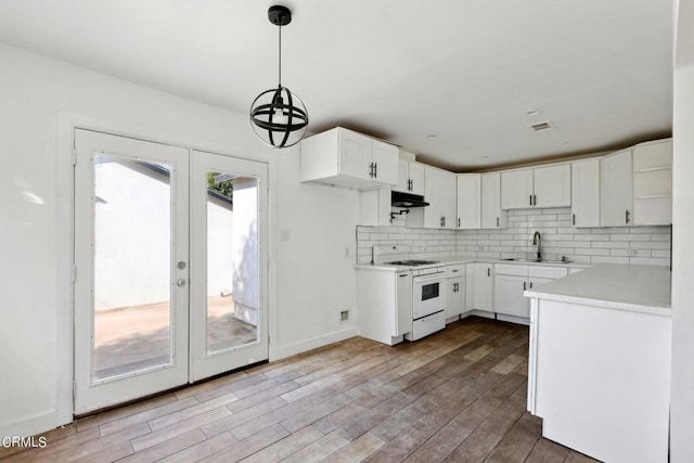 kitchen featuring white cabinets, a healthy amount of sunlight, white range, and hanging light fixtures