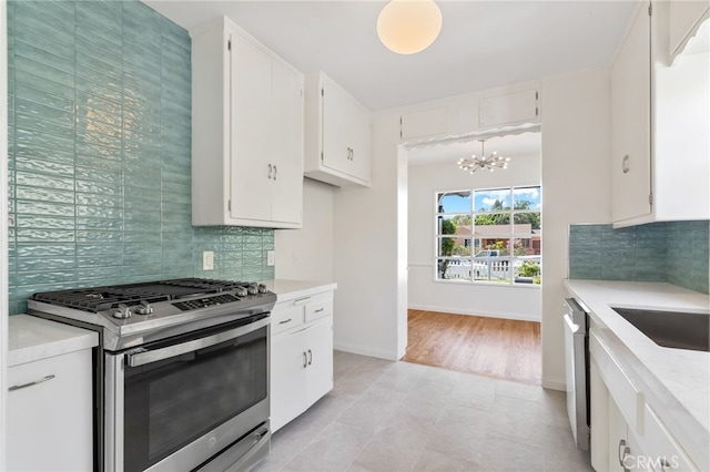 kitchen featuring pendant lighting, tasteful backsplash, white cabinetry, appliances with stainless steel finishes, and an inviting chandelier