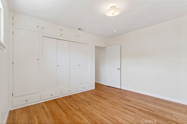 unfurnished bedroom with light wood-type flooring and a closet