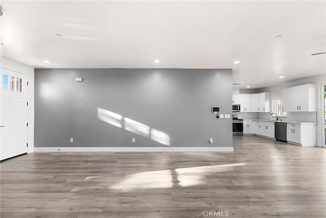 unfurnished living room with light hardwood / wood-style flooring and sink