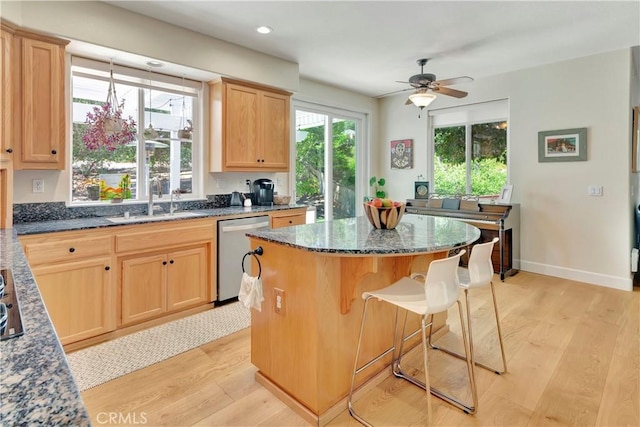 kitchen with a sink, dishwasher, a center island, and light wood finished floors