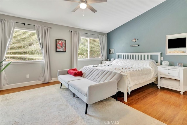 bedroom with vaulted ceiling, wood finished floors, baseboards, and ceiling fan