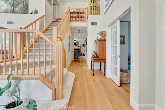 stairway with a fireplace, a high ceiling, wood finished floors, and visible vents