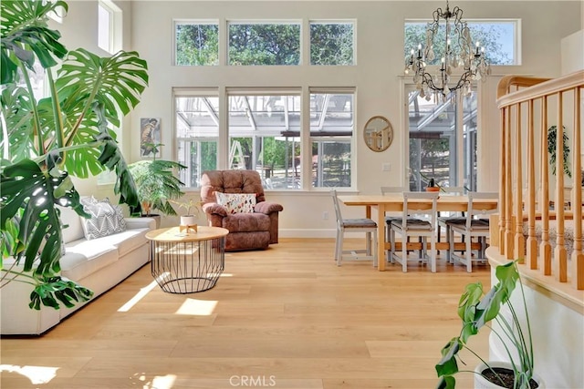 interior space featuring baseboards, an inviting chandelier, wood finished floors, and a towering ceiling