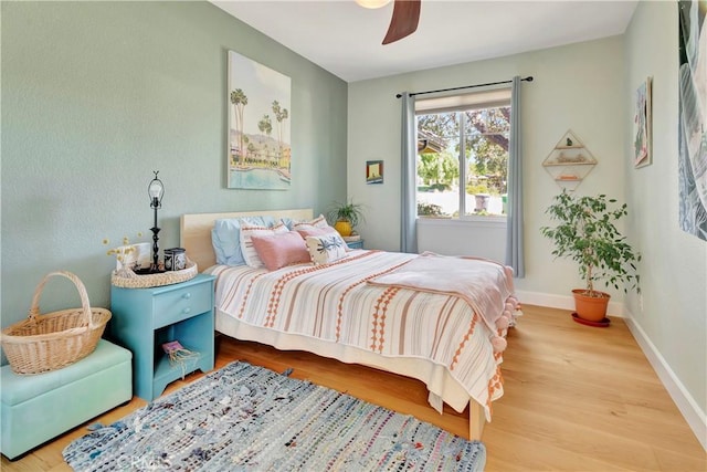 bedroom with baseboards, wood finished floors, and a ceiling fan