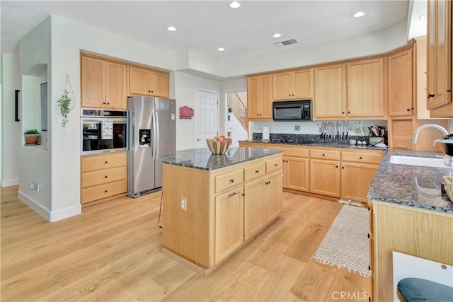 kitchen with light brown cabinetry, appliances with stainless steel finishes, a kitchen island, and a sink